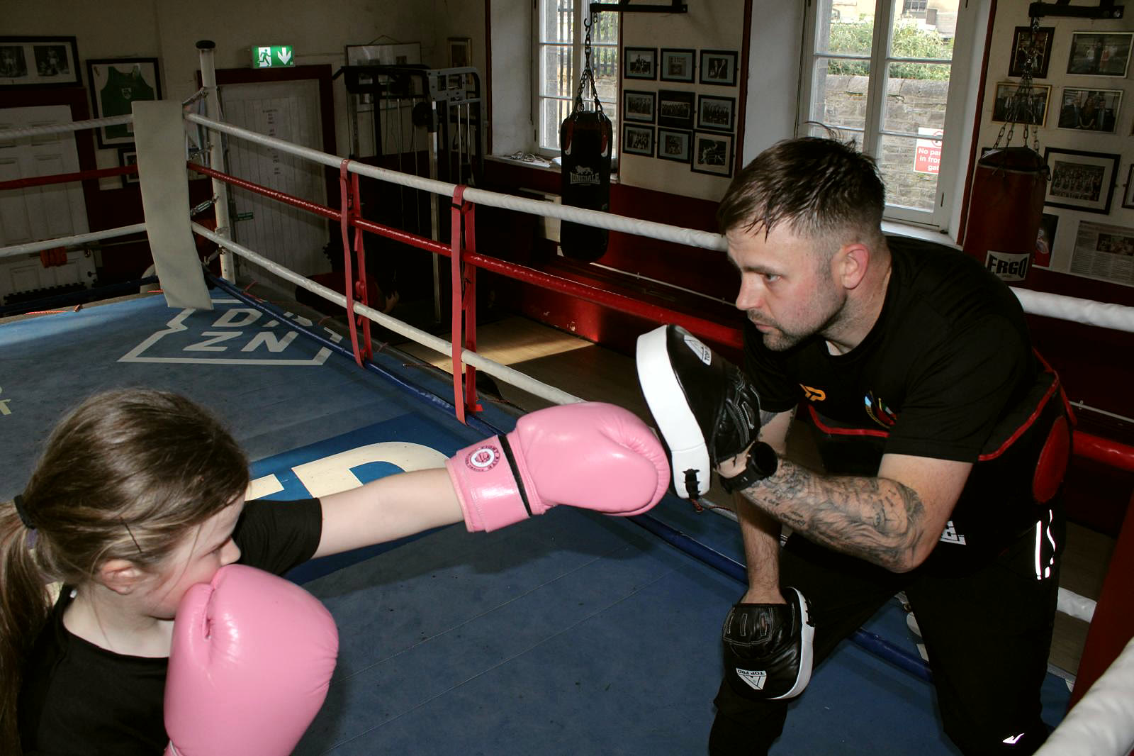 A coach working with a young girl wearing pink gloves
