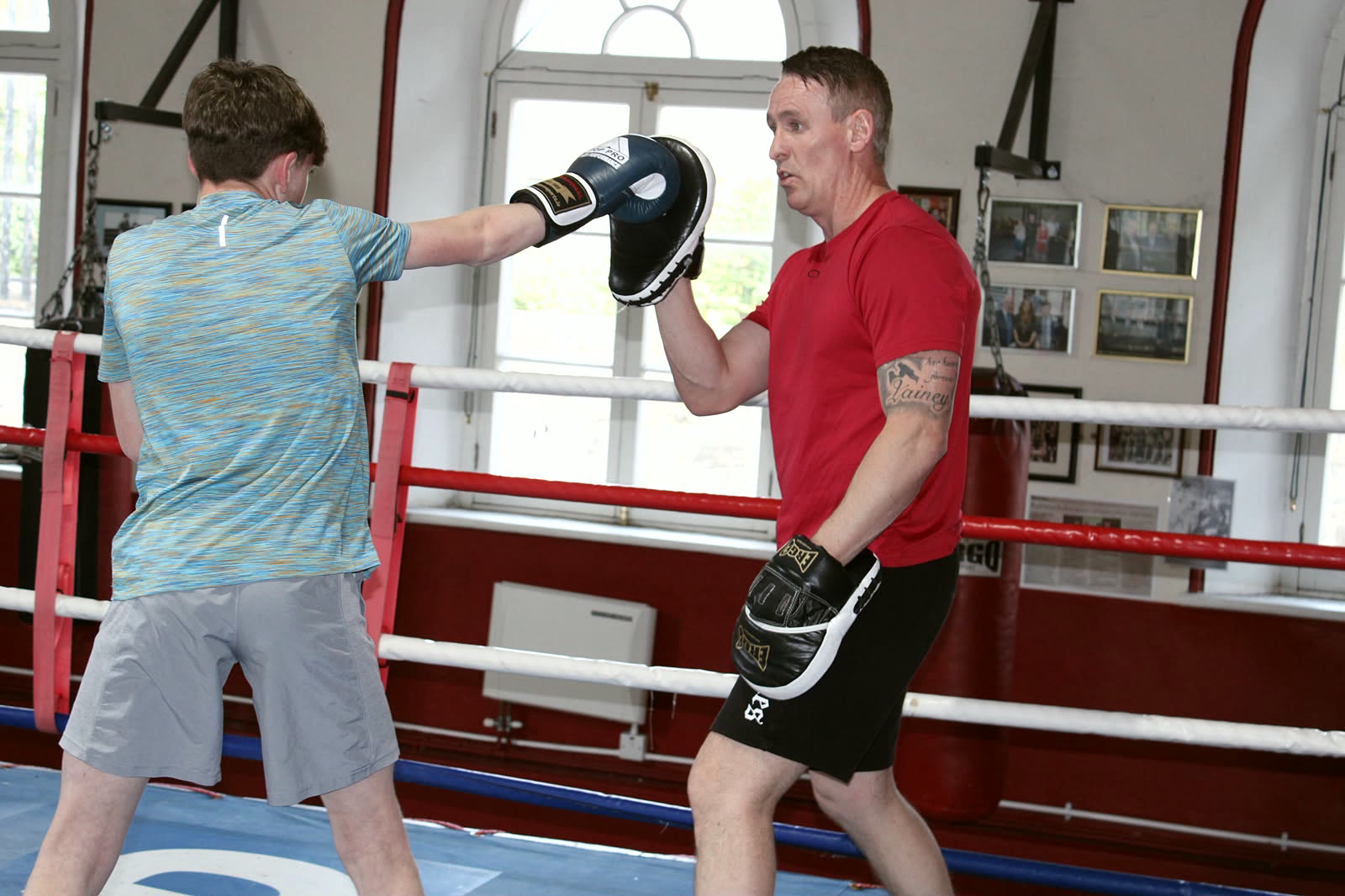 Coach taking a young boxer on the pads in the ring